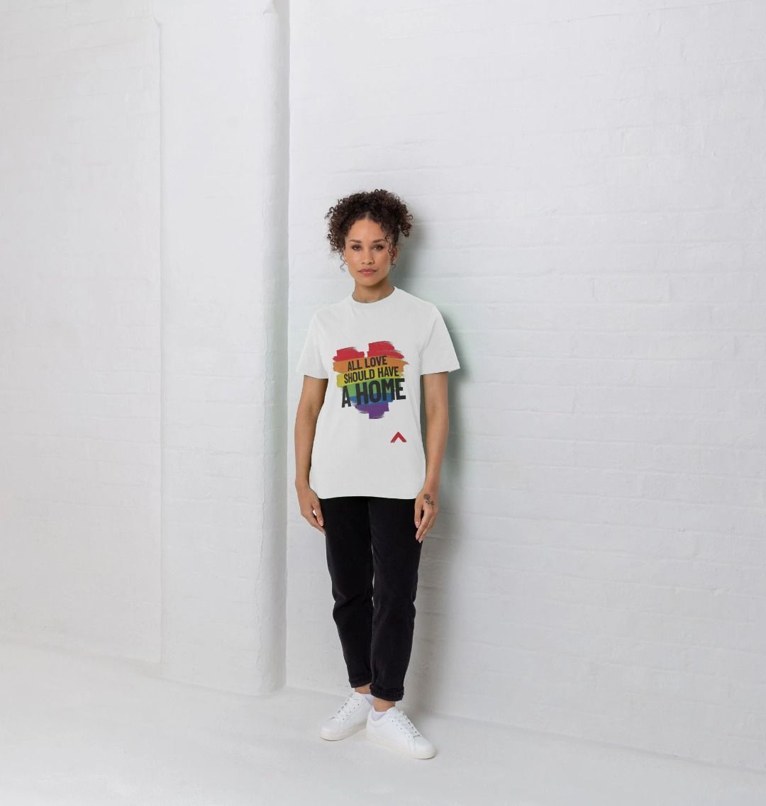 model wearing white all love should have a home t-shirt against a white backdrop, tshirt has a rainbow heart and slogan overlay reads "all love should have a home"