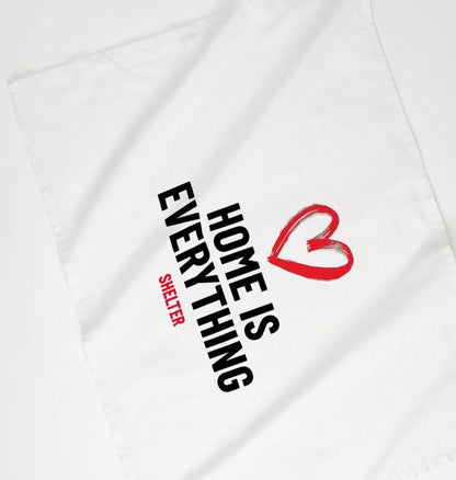 White cotton tea towel with a red heart design and bold, black text which reads 'HOME IS EVERYTHING'