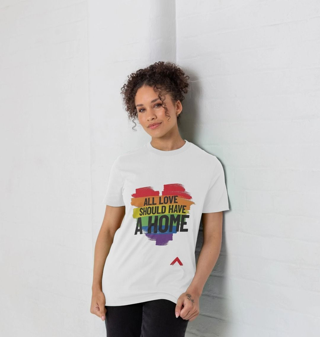 female model wearing white all love should have a home t-shirt. Tshirt has a LBBTQ+ rainbow heart with slogan on front in bold black lettering