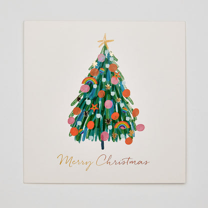 Flat lay christmas card depicting a christmas tree with rainbow pride decorations and text that reads merry christmas
