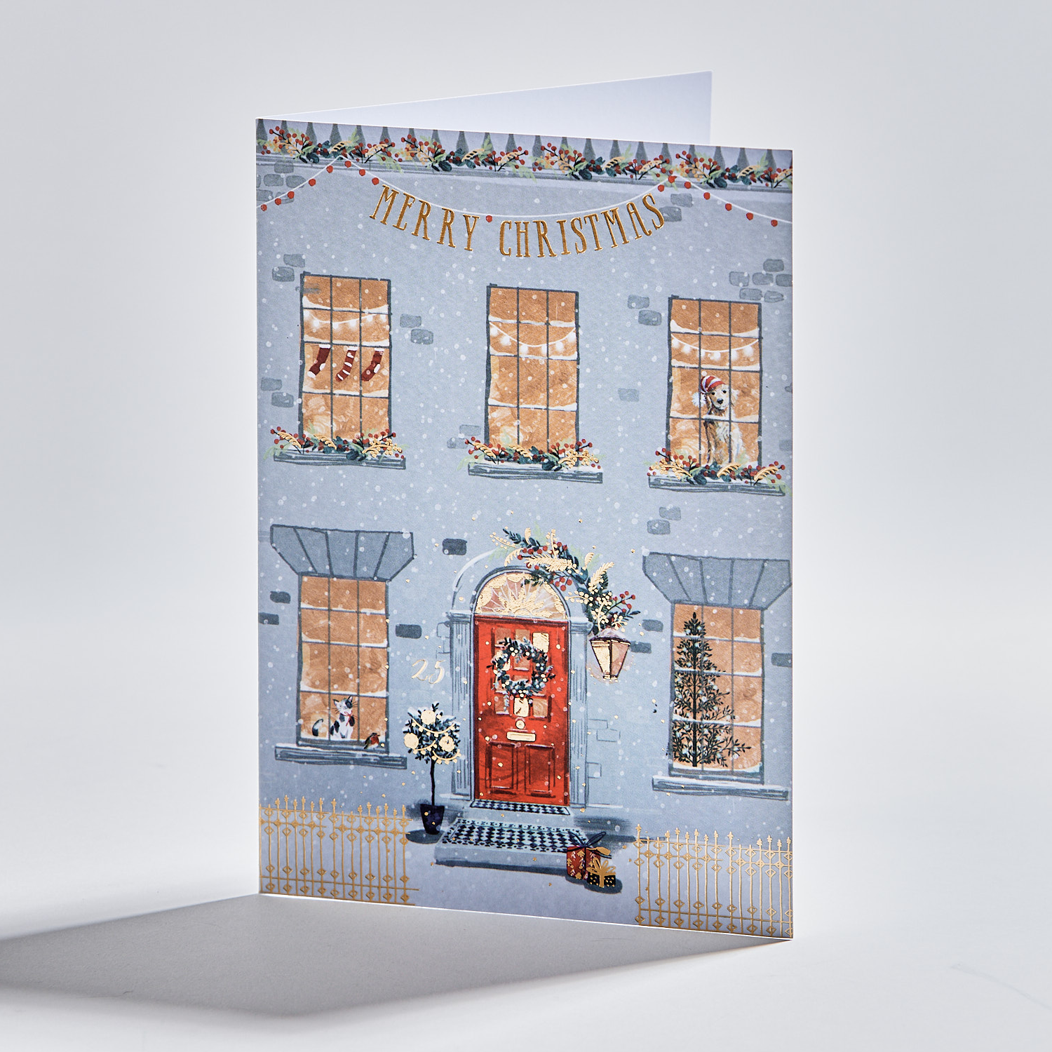 Standing christmas card depicting a townhouse with festive decorations. Text reads 'merry christmas'