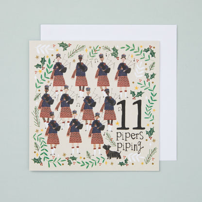 A square Christmas card with an illustration depicting 11 pipers in traditional Scottish dress and a black Scottie dog.