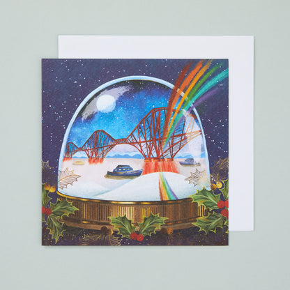 A square Christmas card with an illustration depicting the Forth Bridge in a snowglobe with a rainbow shining out of it.