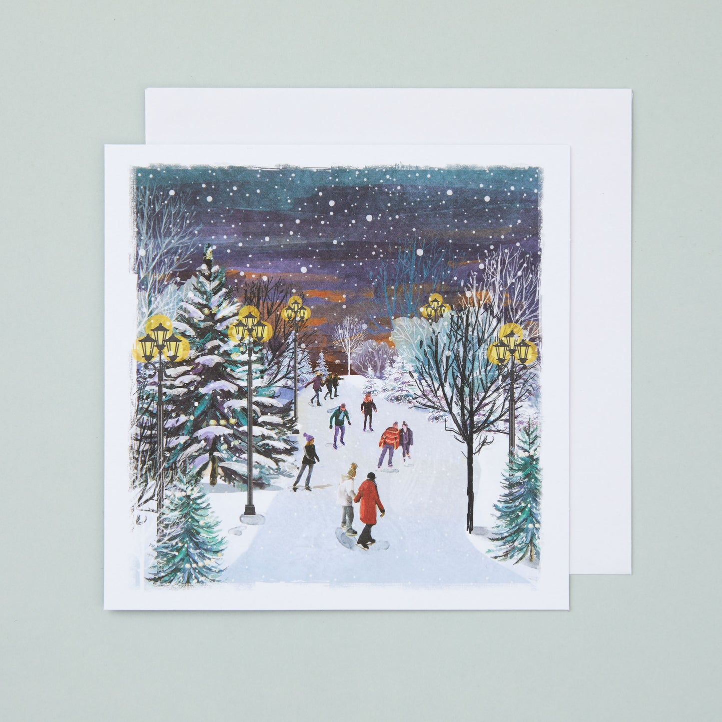 A square Christmas card with an illustration of a snow street scene with people skating along.