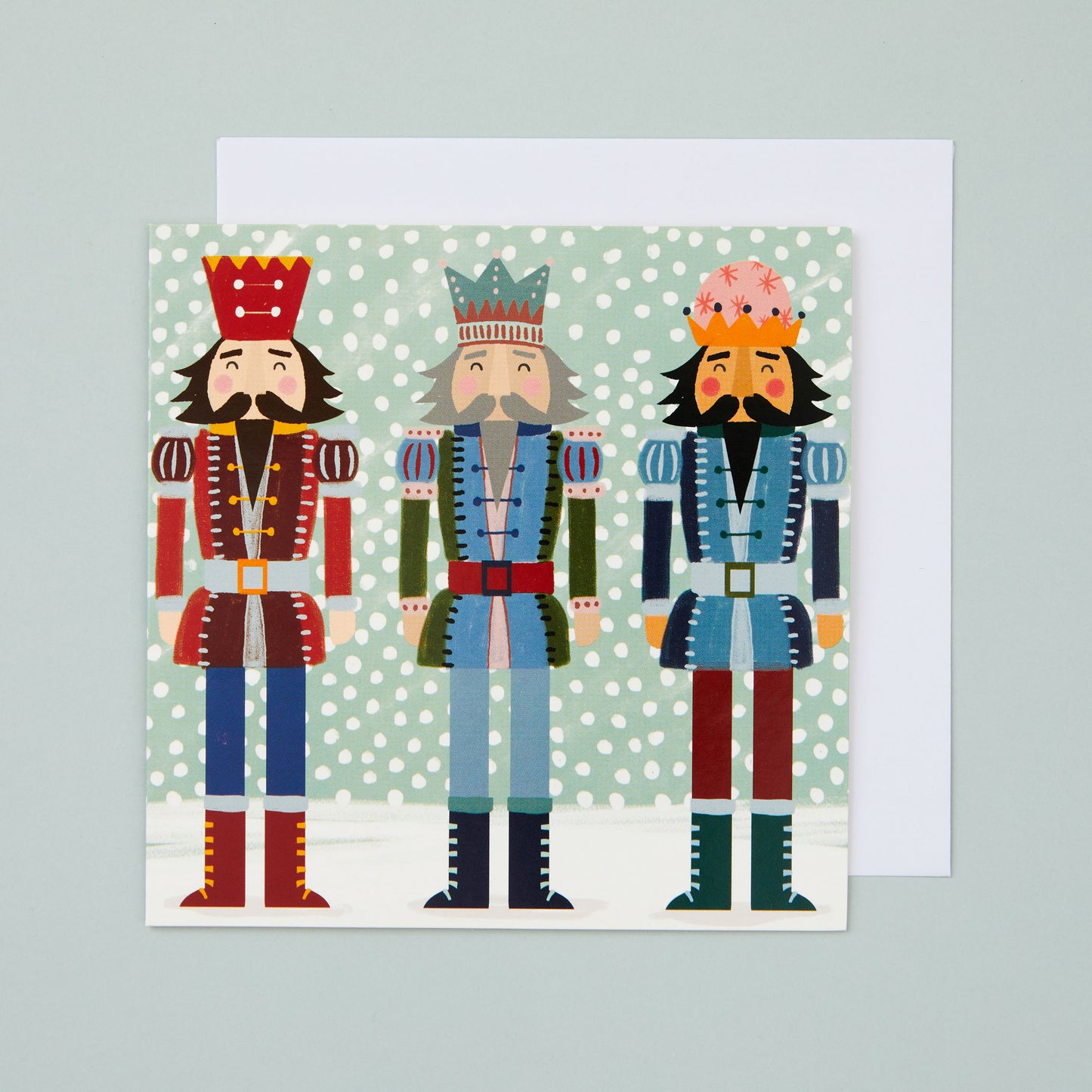 A square Christmas card with an illustration depicting three nutcrackers in the snow.