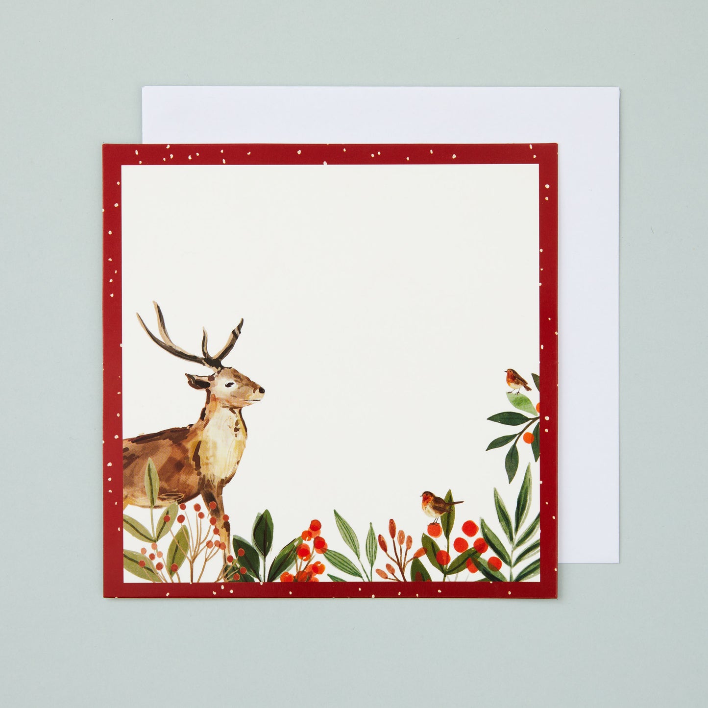 A square flat card with a red border and stag and holly illustrated in the corner. There's a blank section in the middle for your own message.