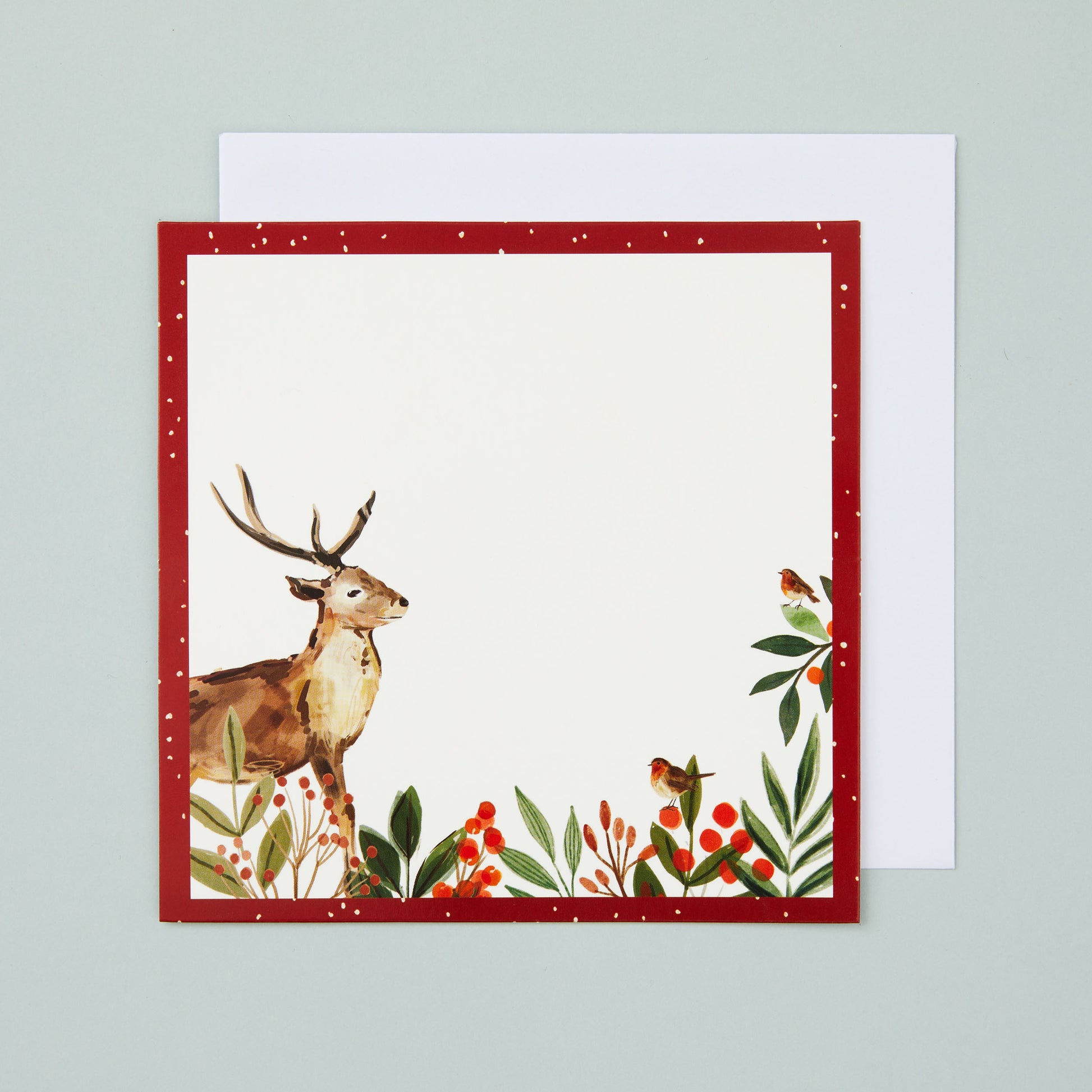 A square flat card with a red border and stag and holly illustrated in the corner. There's a blank section in the middle for your own message.
