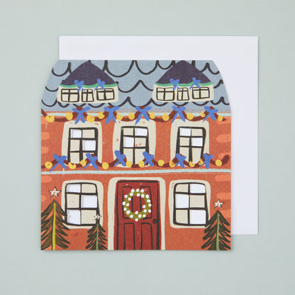 A card shaped like a house, with festive house illustration and die cut windows.