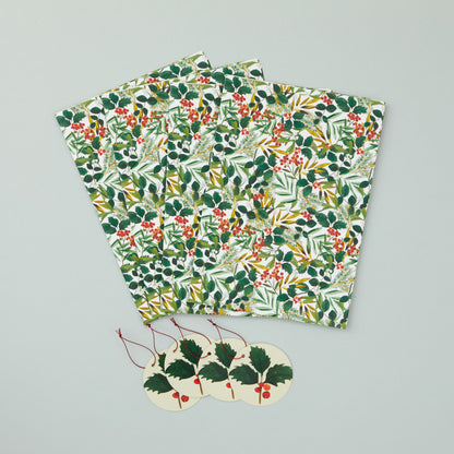 Four sheets of folded foliage wrapping paper with four holly gift tags.