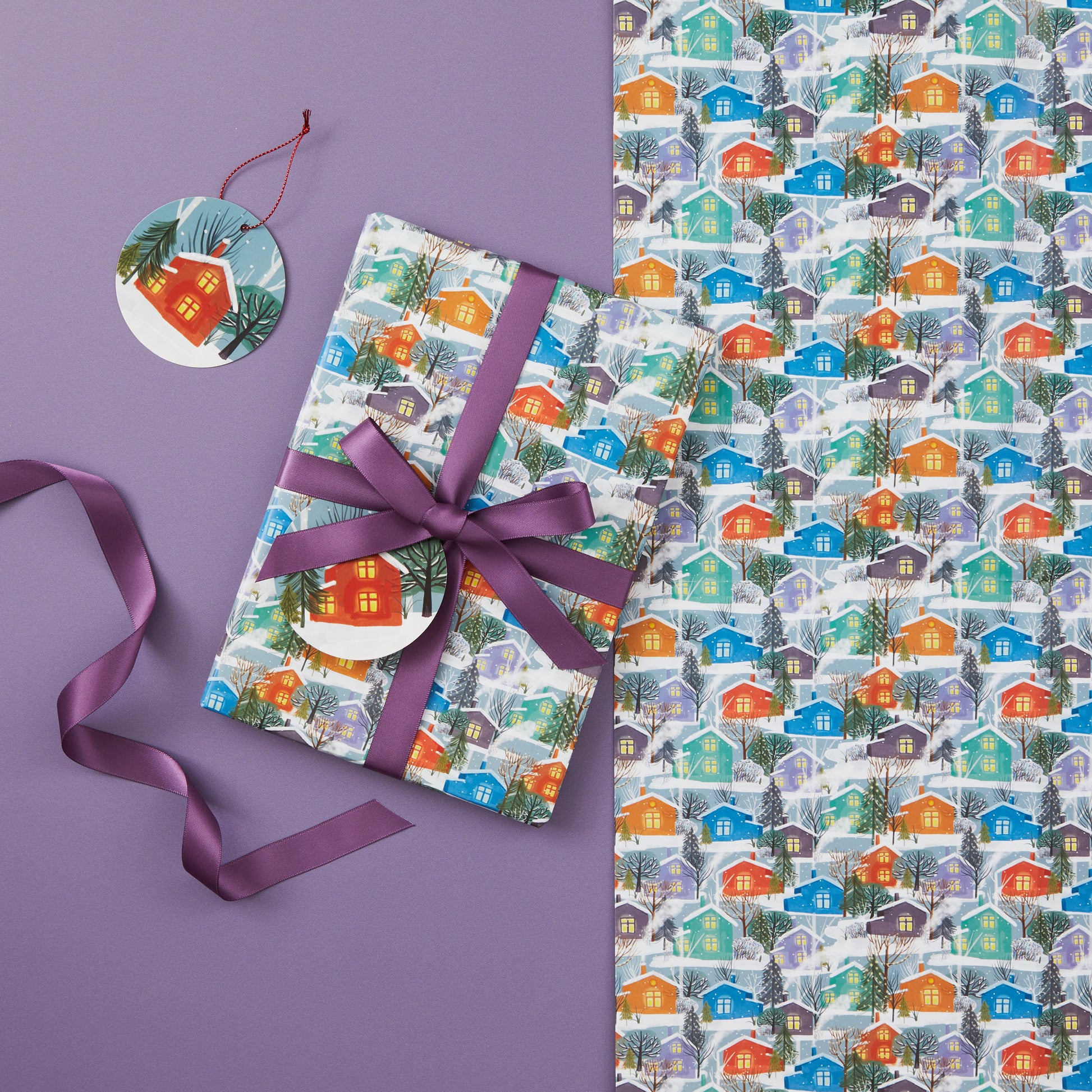 A present wrapped in 'Nordic Houses' gift wrap tied with a lilac ribbon.