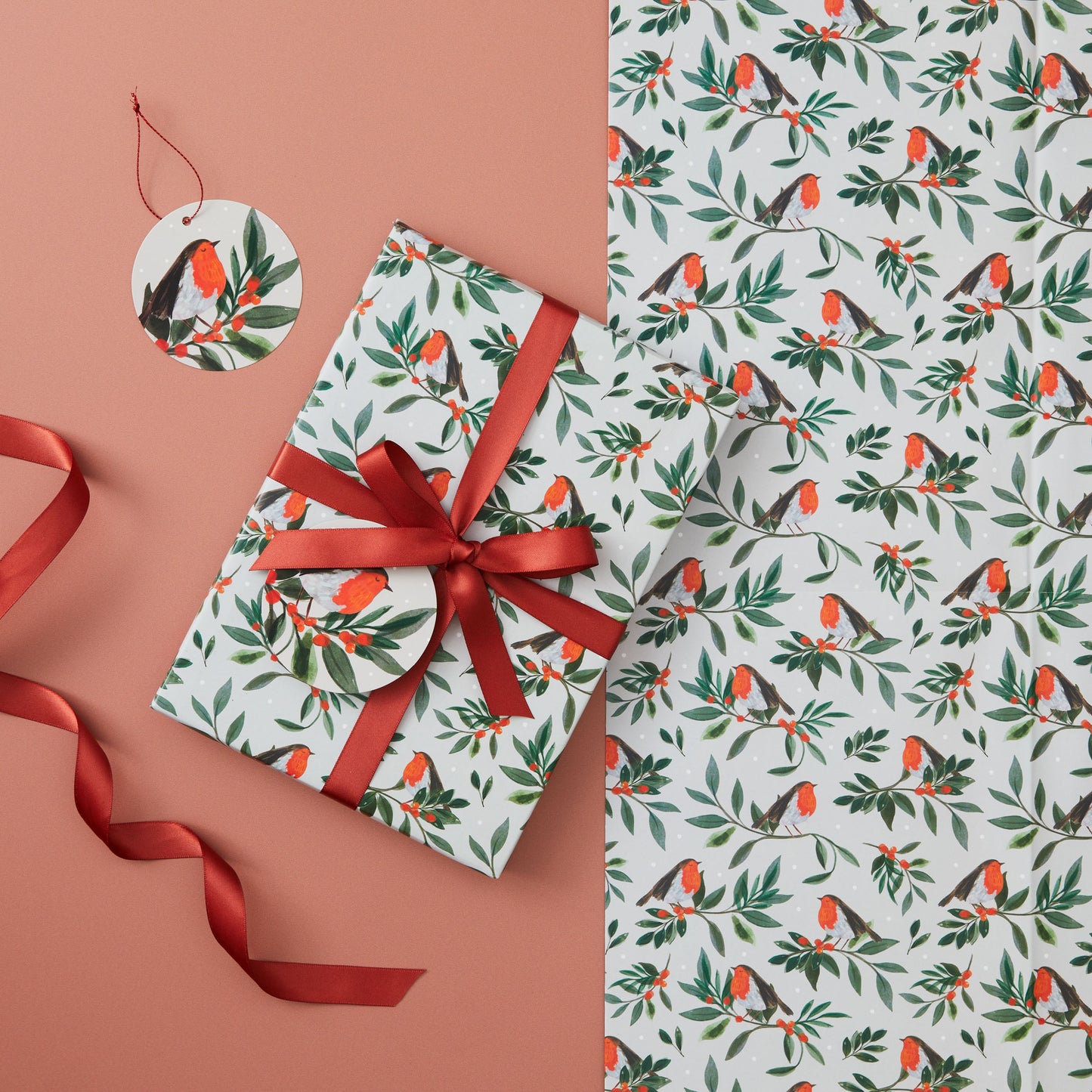 A present wrapped in 'Berry bough' wrapping paper tied with a red ribbon.