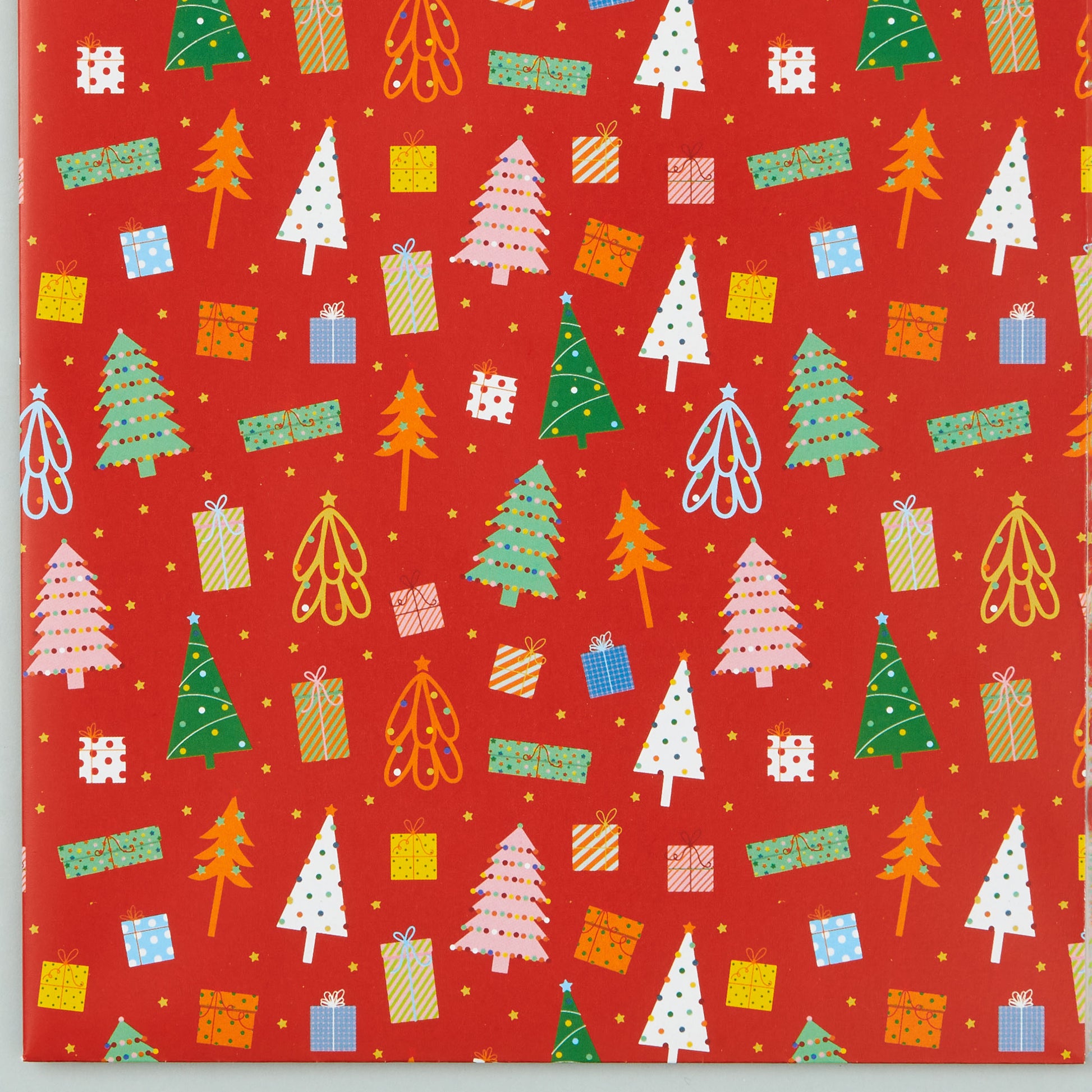 Close up of 'Christmas Trees' design-  a repeat pattern of Christmas trees and present illustrations on a red background. 