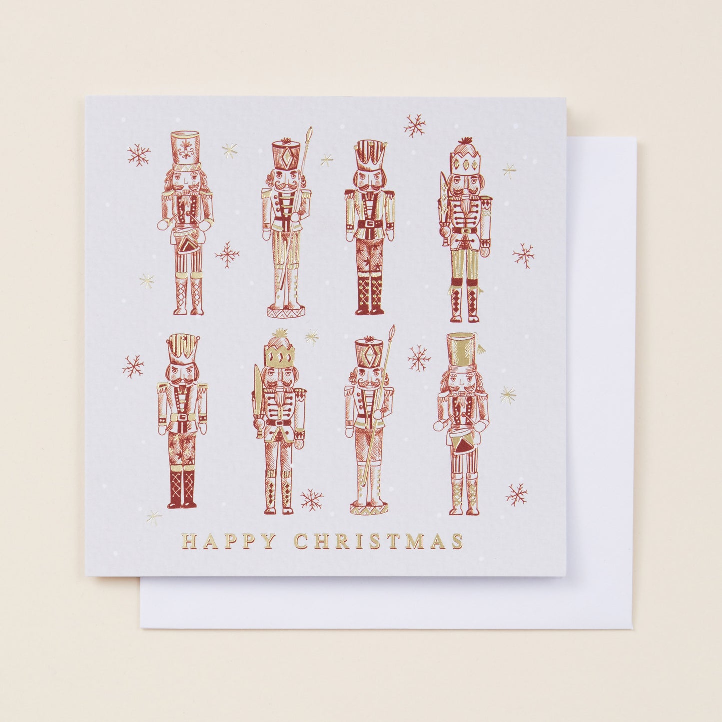 A Christmas card with eight red nutcrackers on the front, the card reading 'Happy Christmas' and sitting on a white envelope.