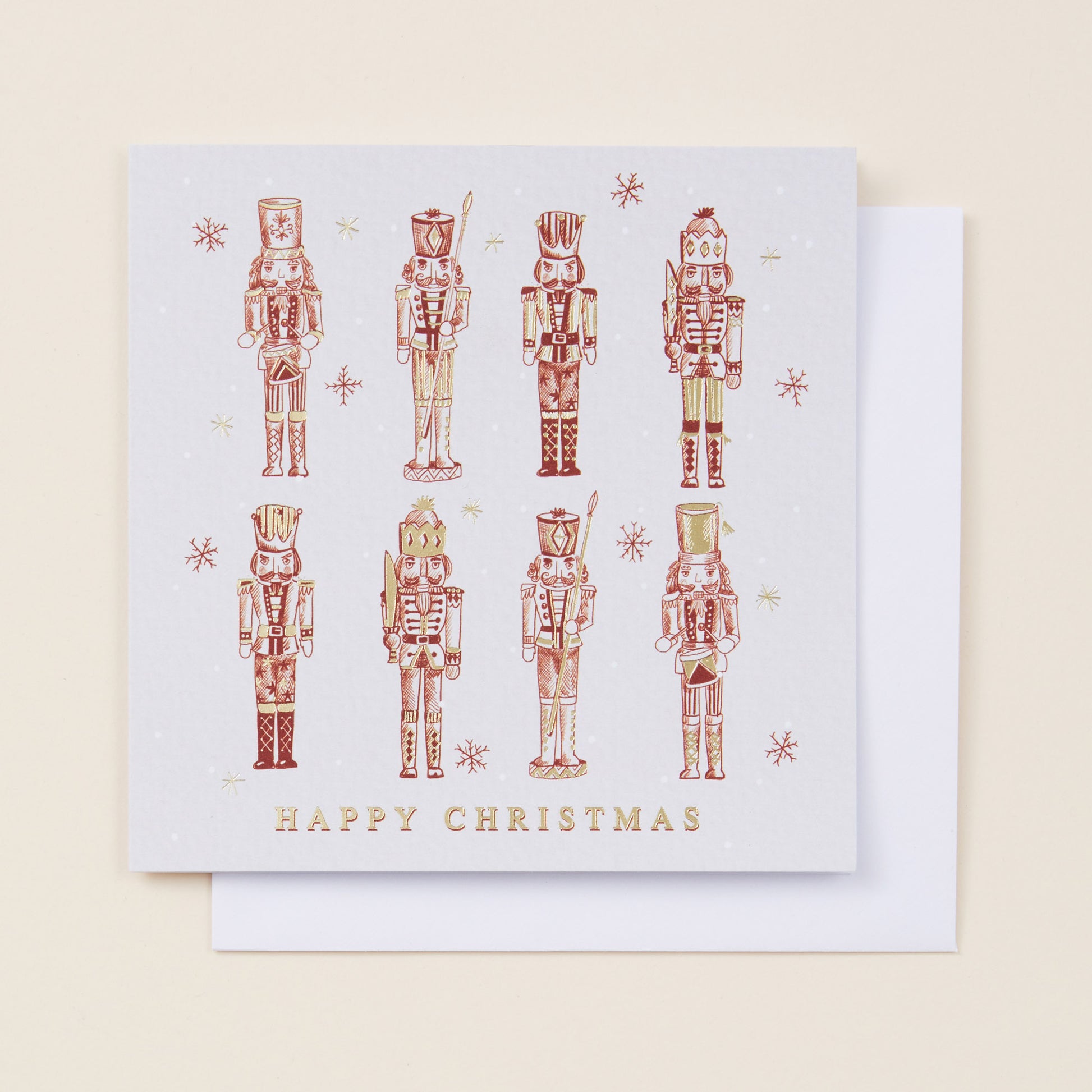 A Christmas card with eight red nutcrackers on the front, the card reading 'Happy Christmas' and sitting on a white envelope.