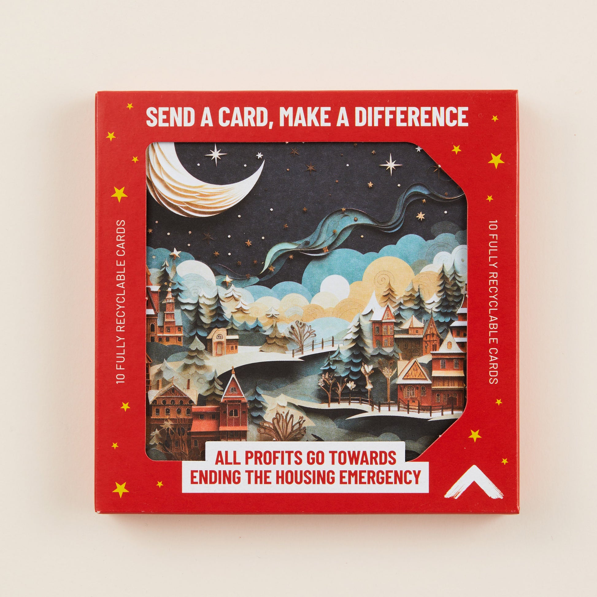 A Christmas card with a scene of a snowy town under a crescent moon on the front, the card shown in red cardboard packaging with the title: 'Send a card, make a difference'