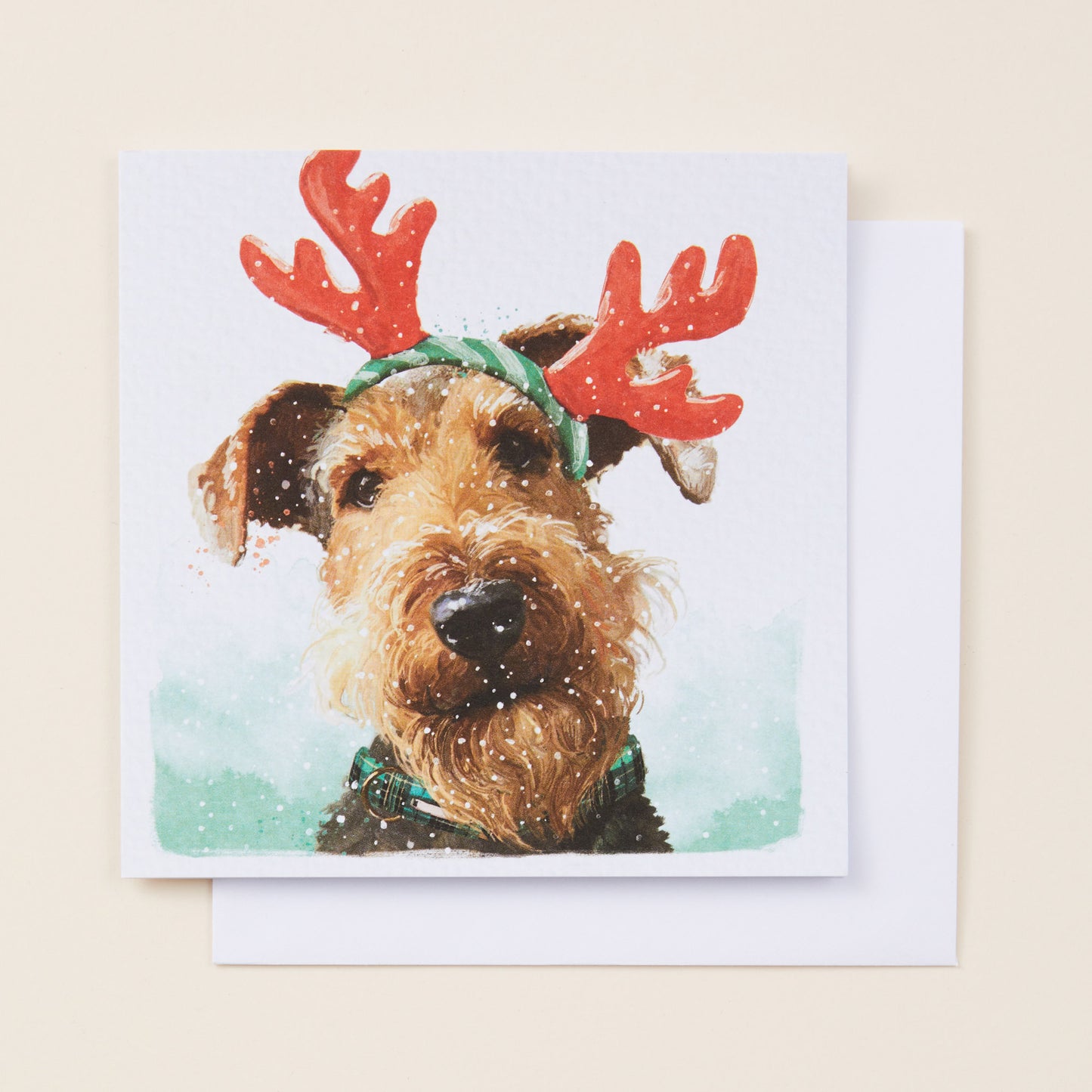 Christmas card with a dog wearing reindeer antlers on a snowy background
