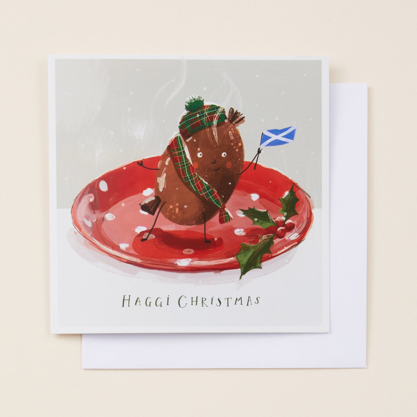 Christmas card with a haggis on a plate, wearing a hat and scarf, with a Scottish flag, on a beige background. Copy reads 'haggi christmas'
