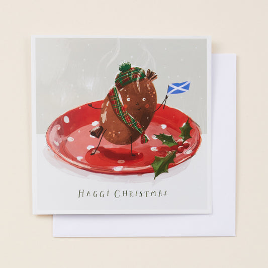 Christmas card with a haggis on a plate, wearing a hat and scarf, with a Scottish flag, on a beige background. Copy reads 'haggi christmas'