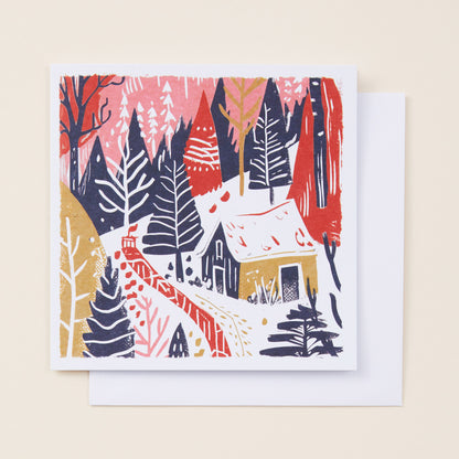 Christmas card with a winter forest design featuring trees and a cabin on a beige background.