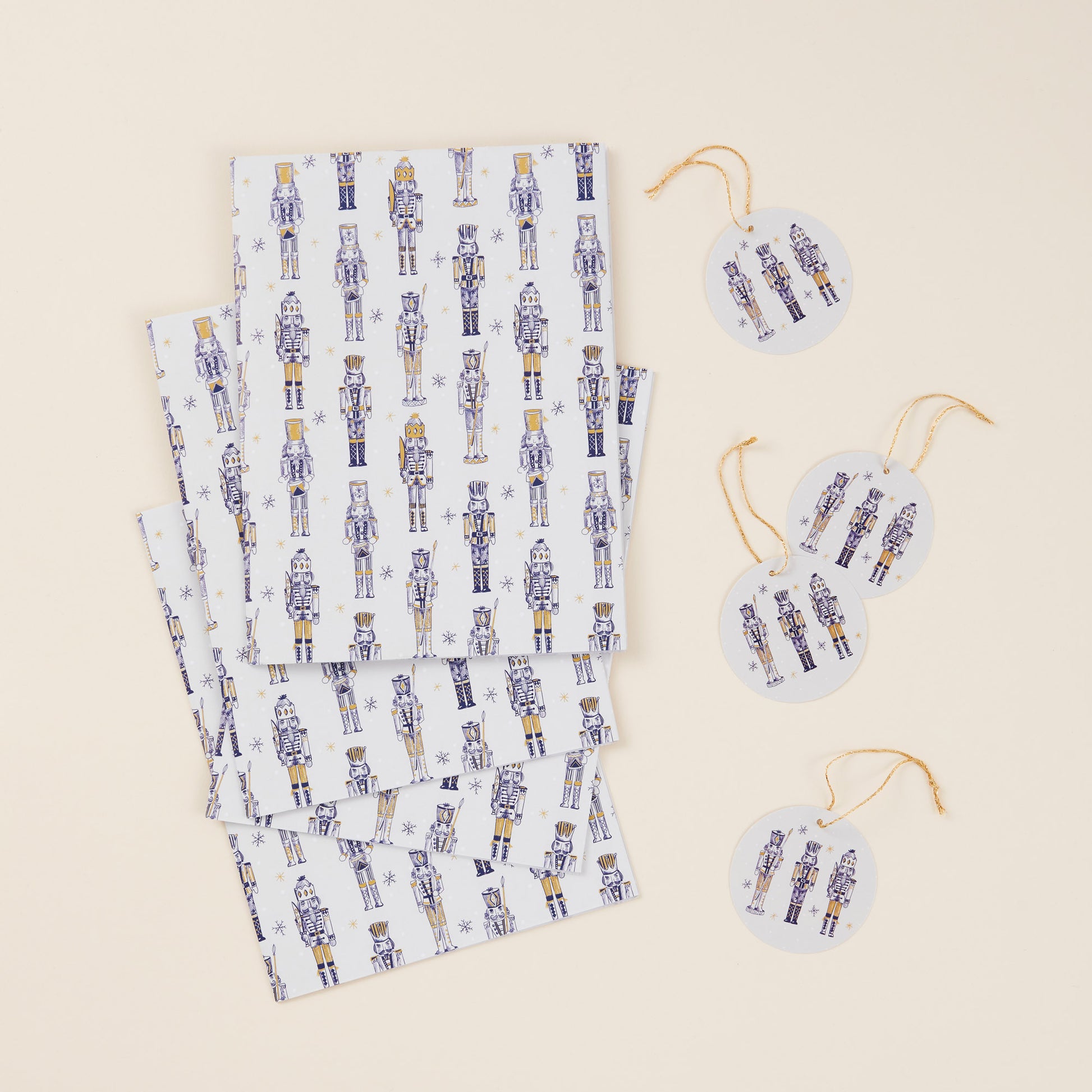 Set of four sheets of wrapping paper and tags with gold string. The design features a gold nutcracker pattern against a white background.