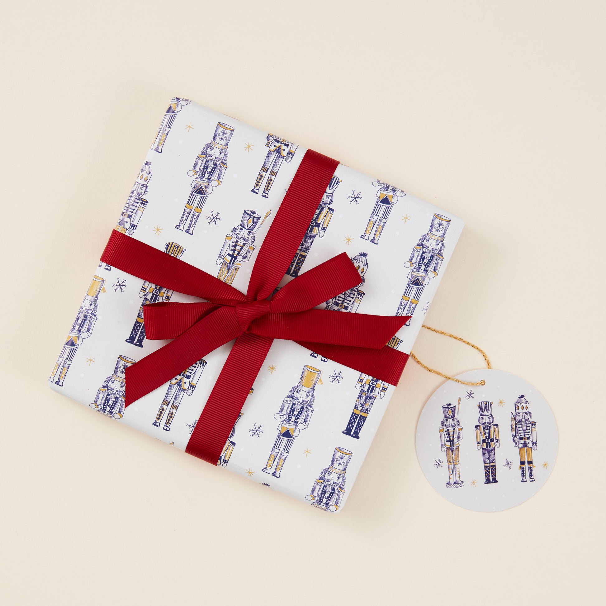 Gift wrapped present in nutcracker-themed paper with a red ribbon on a beige background