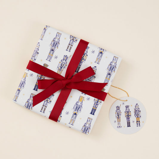 Gift wrapped present in nutcracker-themed paper with a red ribbon on a beige background