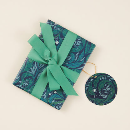 Gift wrapped in blue floral paper with a green ribbon on a beige background