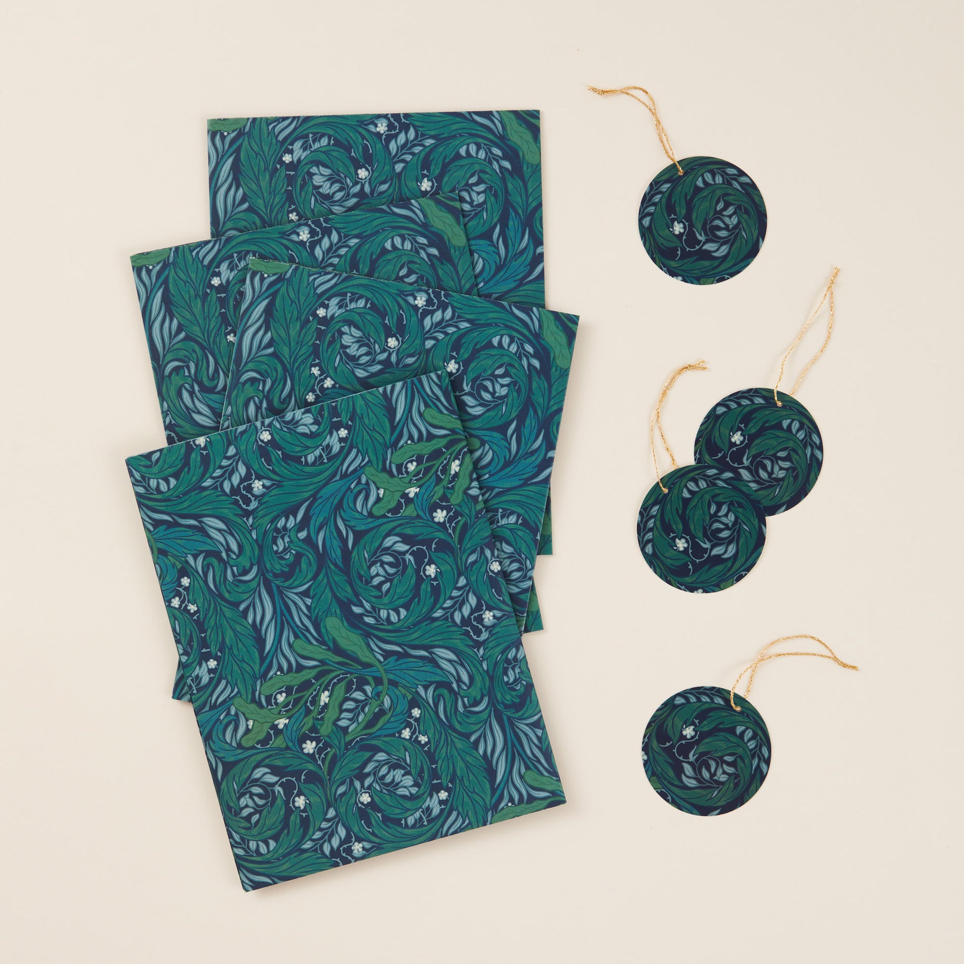 Four sheets of green nature patterned wrapping paper with four tags with gold strings