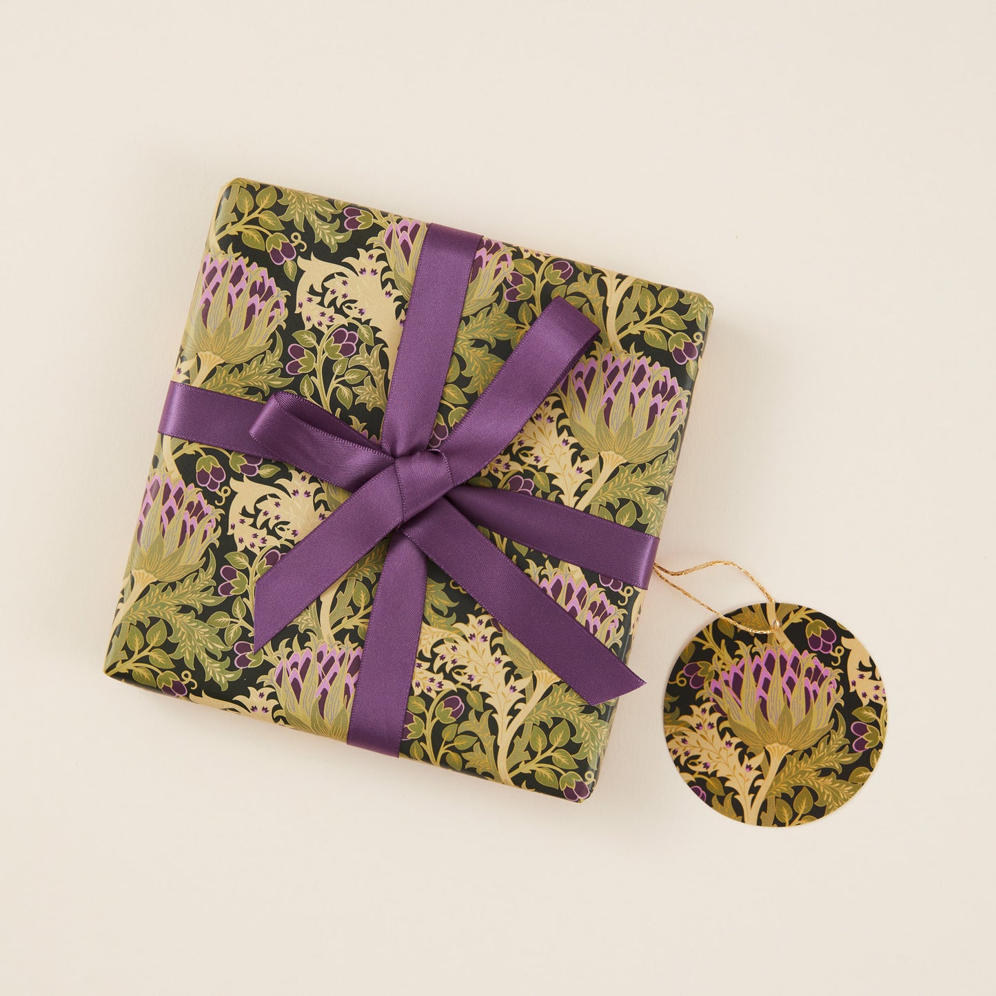 Gift wrapped in floral paper with a purple ribbon on a beige background