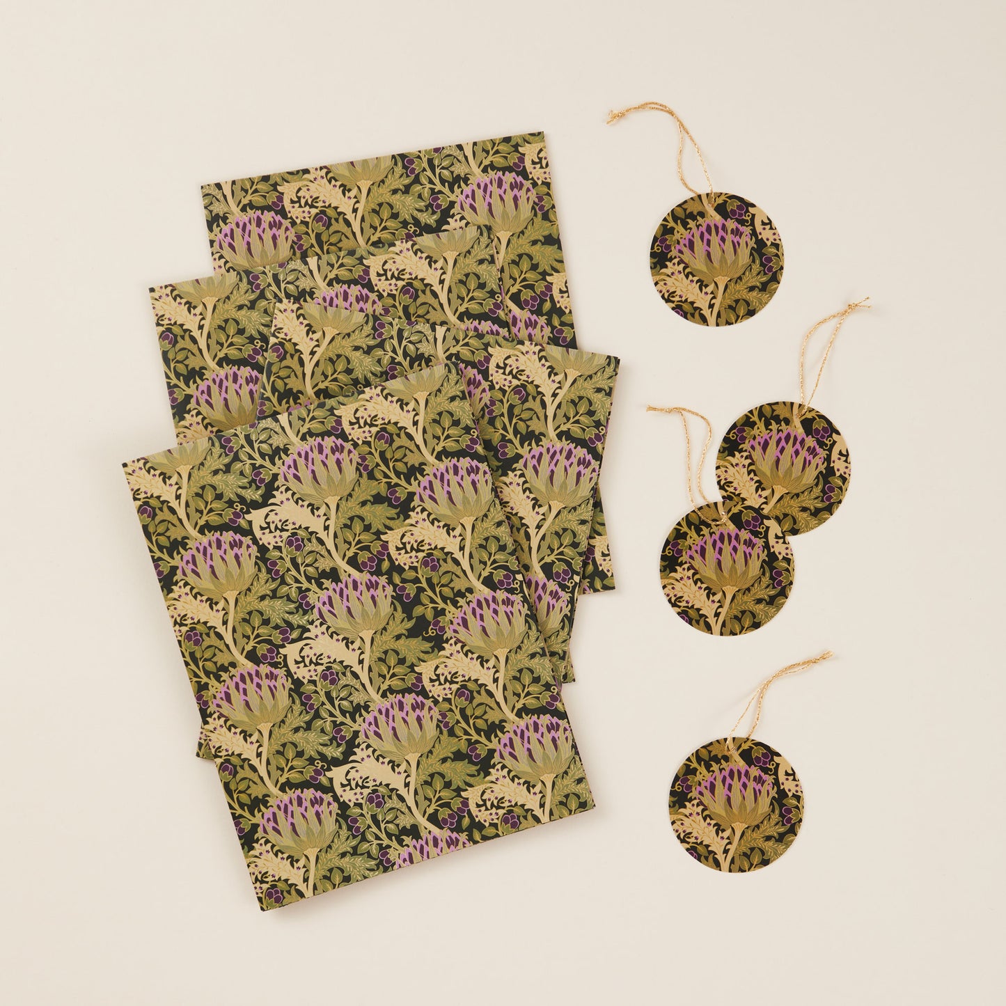 Four sheets of vintage thistle patterned gift wrap alongside four matching gift tags with gold string.