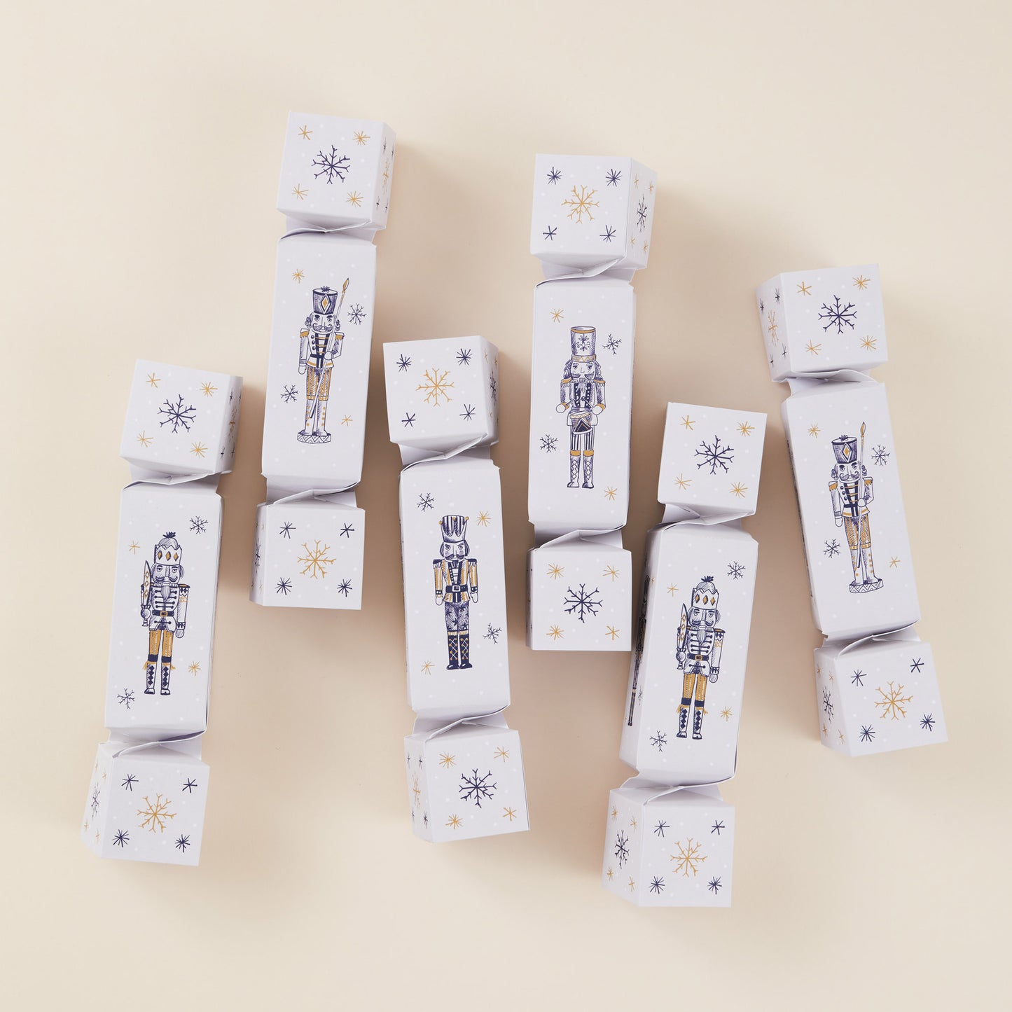 Six Christmas crackers with nutcracker and snowflake designs on a beige background