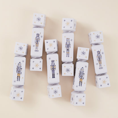 Six Christmas crackers with nutcracker and snowflake designs on a beige background