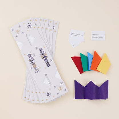 Six flat pack Christmas crackers with nutcracker design, shown alongside coloured paper hats and joke inserts