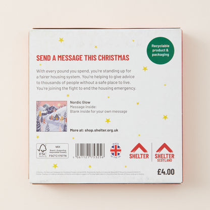 The back of a white rectangular product box with red border, featuring holiday-themed messaging text, a small snowy illustration, a barcode, UK logos, and Shelter branding on a light beige background.