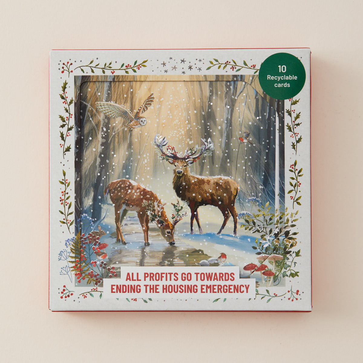 A square printed card set box shown against a plain warm beige background. The front artwork depicts a snowy forest scene with two deer, a bird, and floral border details.