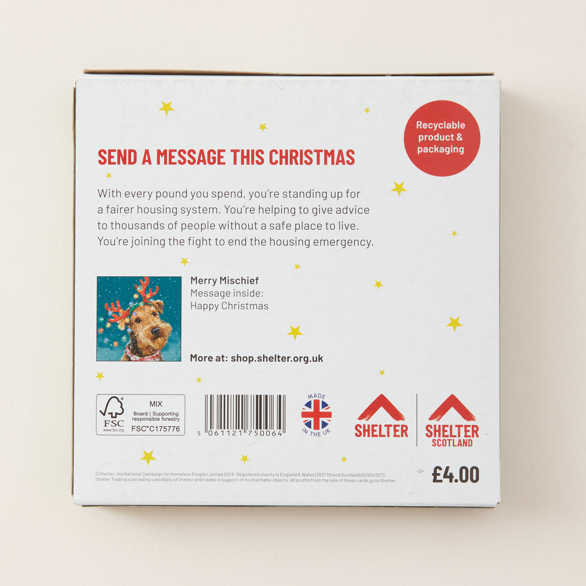 The back of a white SHELTER Christmas message box, featuring red and black text, a small festive illustration, and recycling and UK certification logos on a light beige background.