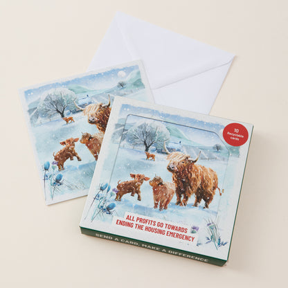 A boxed set of winter-themed cards and envelopes shown on a light beige background. The front card box features an illustration of Highland cows and calves in a snowy landscape.