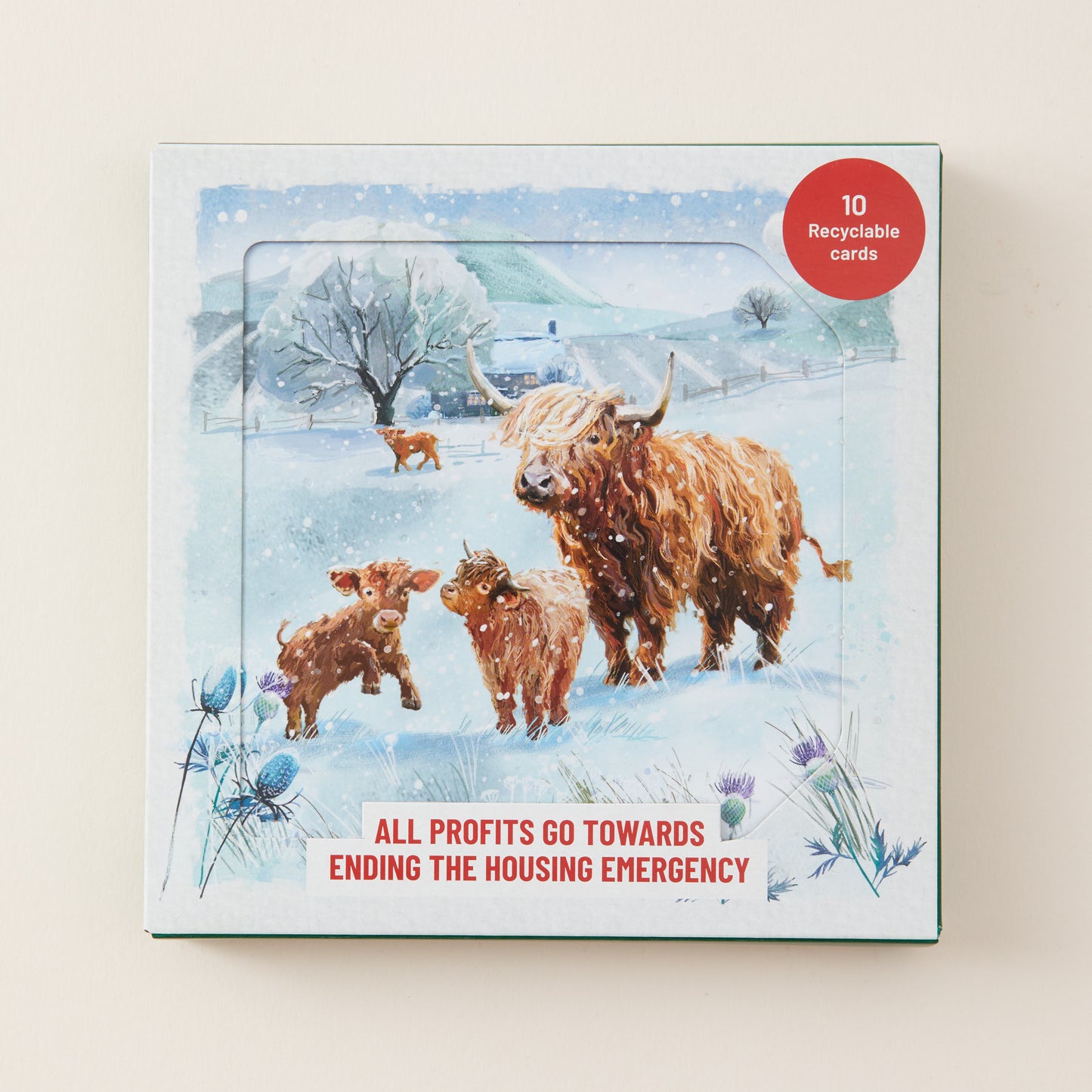 A square card deck box with a winter illustration showing a Highland cow, calf, and lamb in snow, plus a red circular badge reading '10 Recyclable Cards' and text at the bottom about ending the housing emergency.