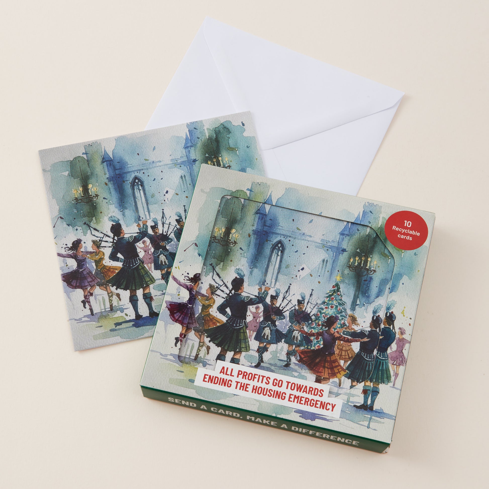 A set of protest art cards and envelopes featuring a watercolor painting of Scottish dancers in traditional attire around a Christmas tree. The main card is shown in front with its envelope, on a light beige background.