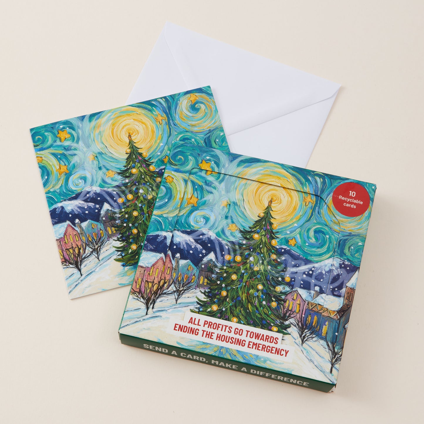 A boxed card set with a matching envelope, featuring a stylized snowy village scene inspired by Van Gogh's Starry Night, with a red circular badge reading '10 recyclable cards' and the text 'SEND A CARD, MAKE A DIFFERENCE' on the box.
