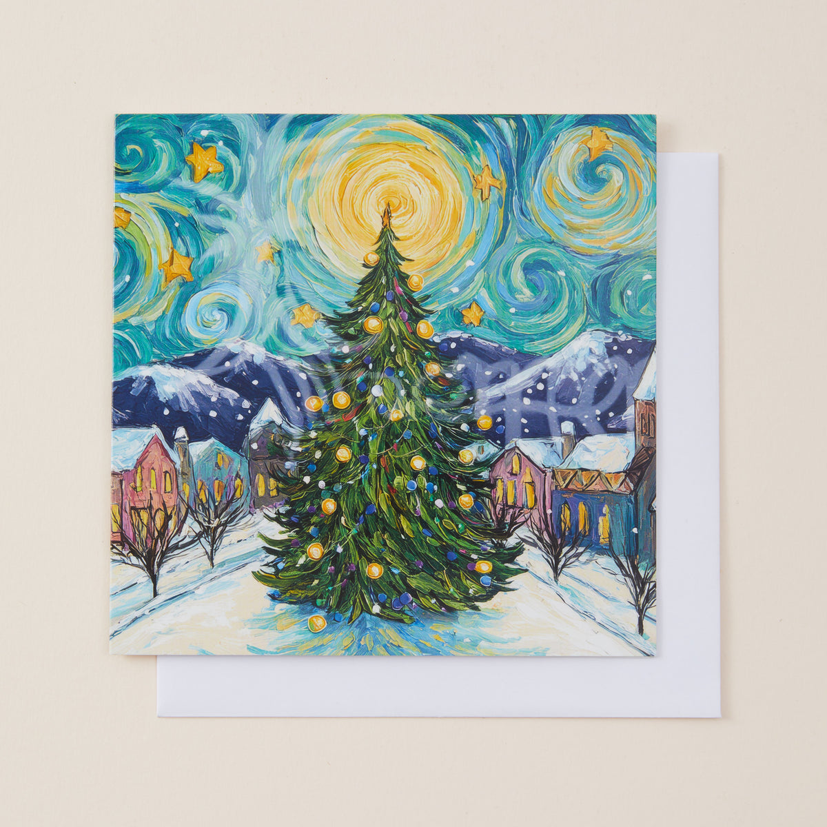 A square art print or card featuring a whimsical Christmas village scene in a swirling, Van Gogh-inspired style, with a decorated evergreen tree in the foreground, mountains, houses, and a bright yellow starry sky. A white envelope is partially visible behind it on a light beige background.