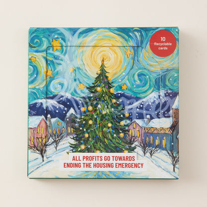 A square printed card set box featuring a stylized snowy village scene with a decorated Christmas tree, mountains, and swirling sky in a starry art style. A red circular badge says '10 Recyclable Cards,' and text at the bottom reads 'ALL PROFITS GO TOWARDS ENDING THE HOUSING EMERGENCY.
