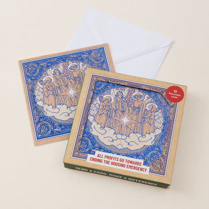 A boxed greeting card set on a warm cream background, with two square cards featuring a blue and gold religious illustration and a white envelope behind them.