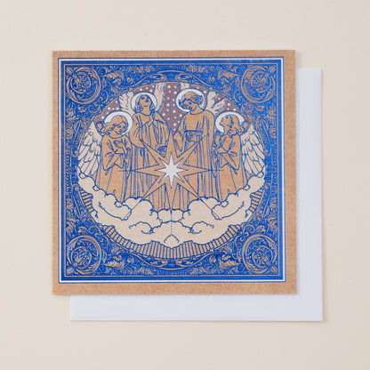 A square art print or card featuring a blue and tan illustration of three angels with a central star and clouds, shown with a white envelope behind it on a light beige background.