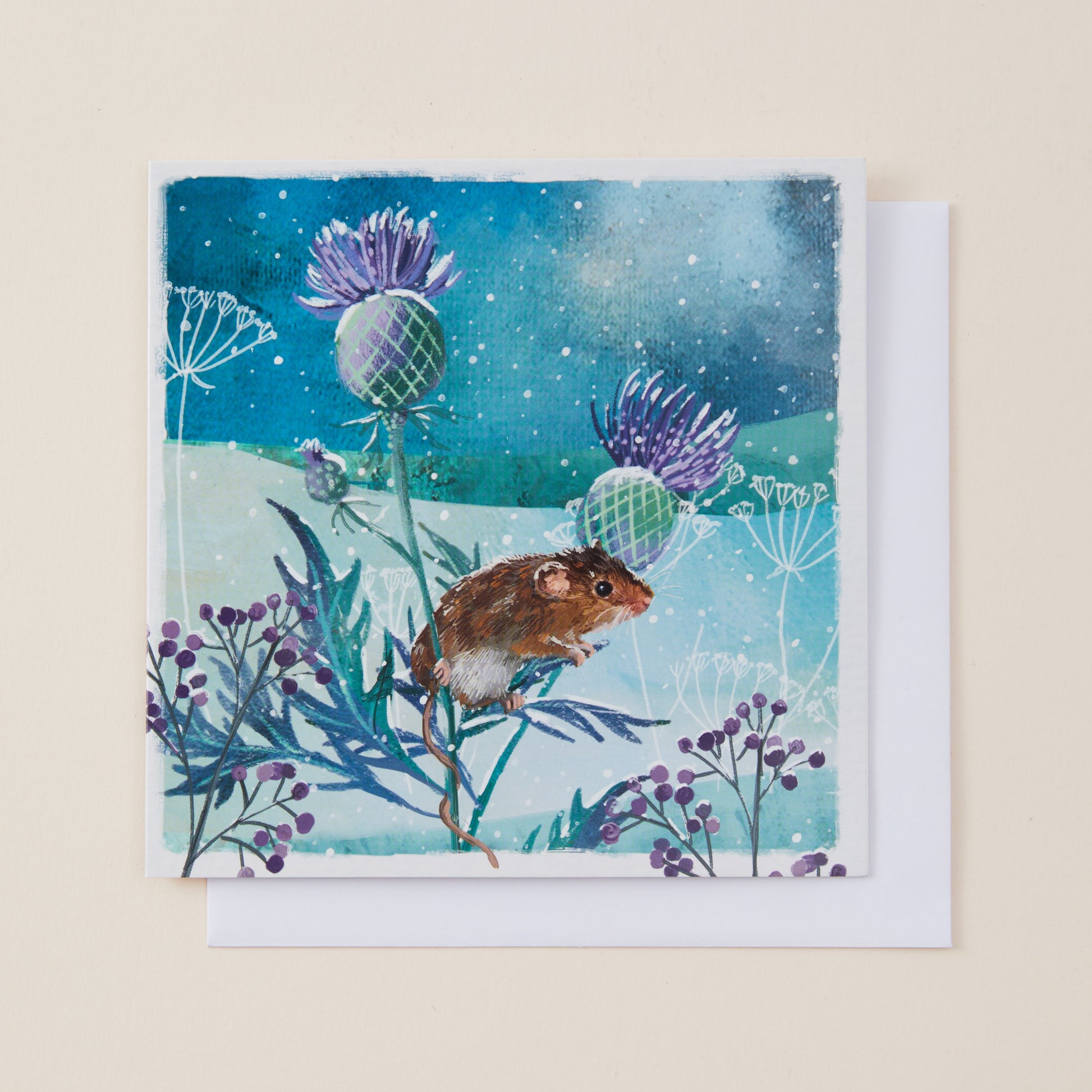 A square art print or card featuring a painted scene of a brown mouse among purple flowers and blue-green plants under a starry night sky, shown with a white envelope behind it on a light beige background.