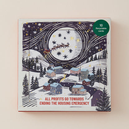 A square Christmas-themed card set box with illustrated snowy houses under a starry night sky and Santa flying, plus a green circular badge reading '10 Recyclable cards.' Text at the bottom says 'ALL PROFITS GO TOWARDS ENDING THE HOUSING EMERGENCY.