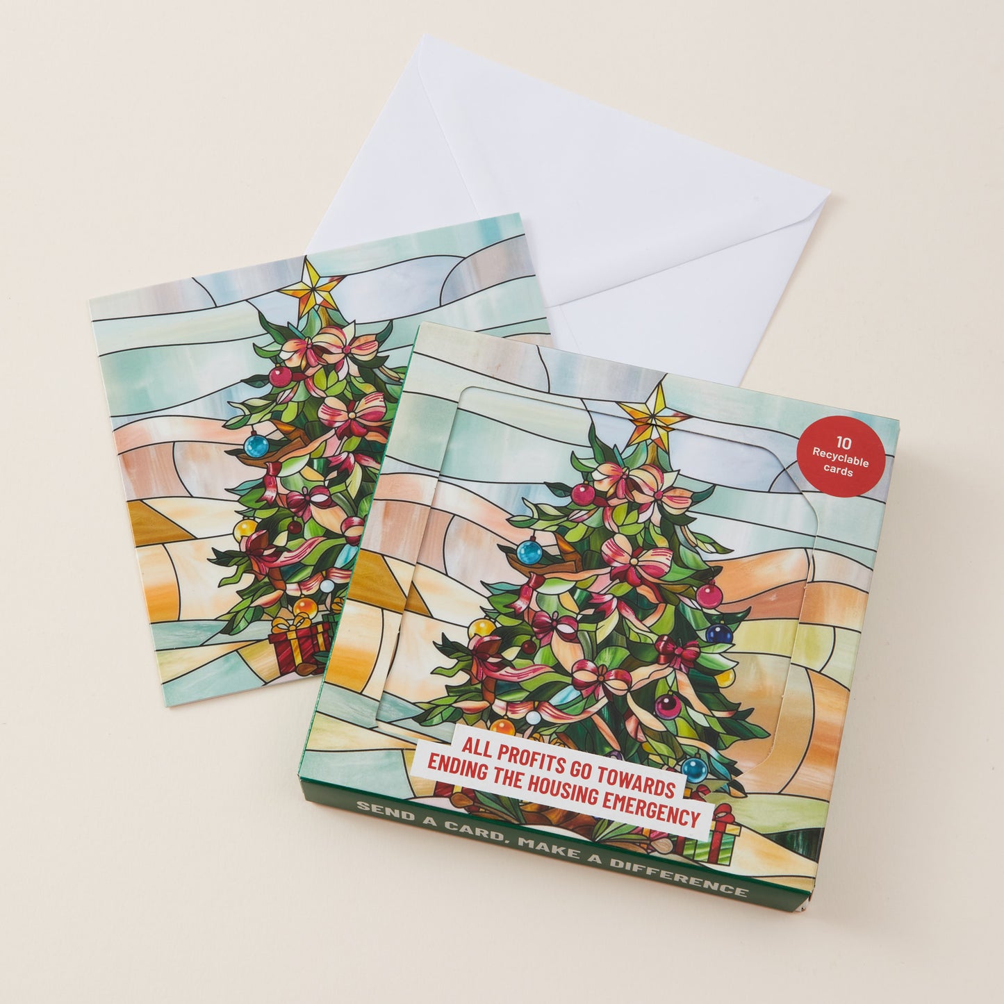 A set of three Christmas-themed greeting cards with a white envelope, featuring a stained-glass style illustration of a decorated Christmas tree and the text 'ALL PROFITS GO TOWARDS ENDING THE HOUSING EMERGENCY'.
