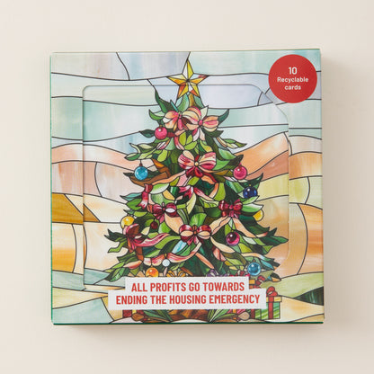 A square Christmas-themed card set box with a stained-glass style illustration of a decorated tree, a gold star, and a red circular badge that says '10 Recyclable cards.' The front also reads, 'ALL PROFITS GO TOWARDS ENDING THE HOUSING EMERGENCY.