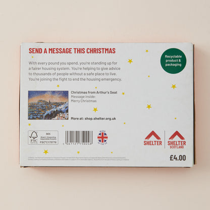 The back of a white cardboard box for Shelter Scotland, featuring red and green text, a small illustration, and a barcode, photographed against a light beige background.