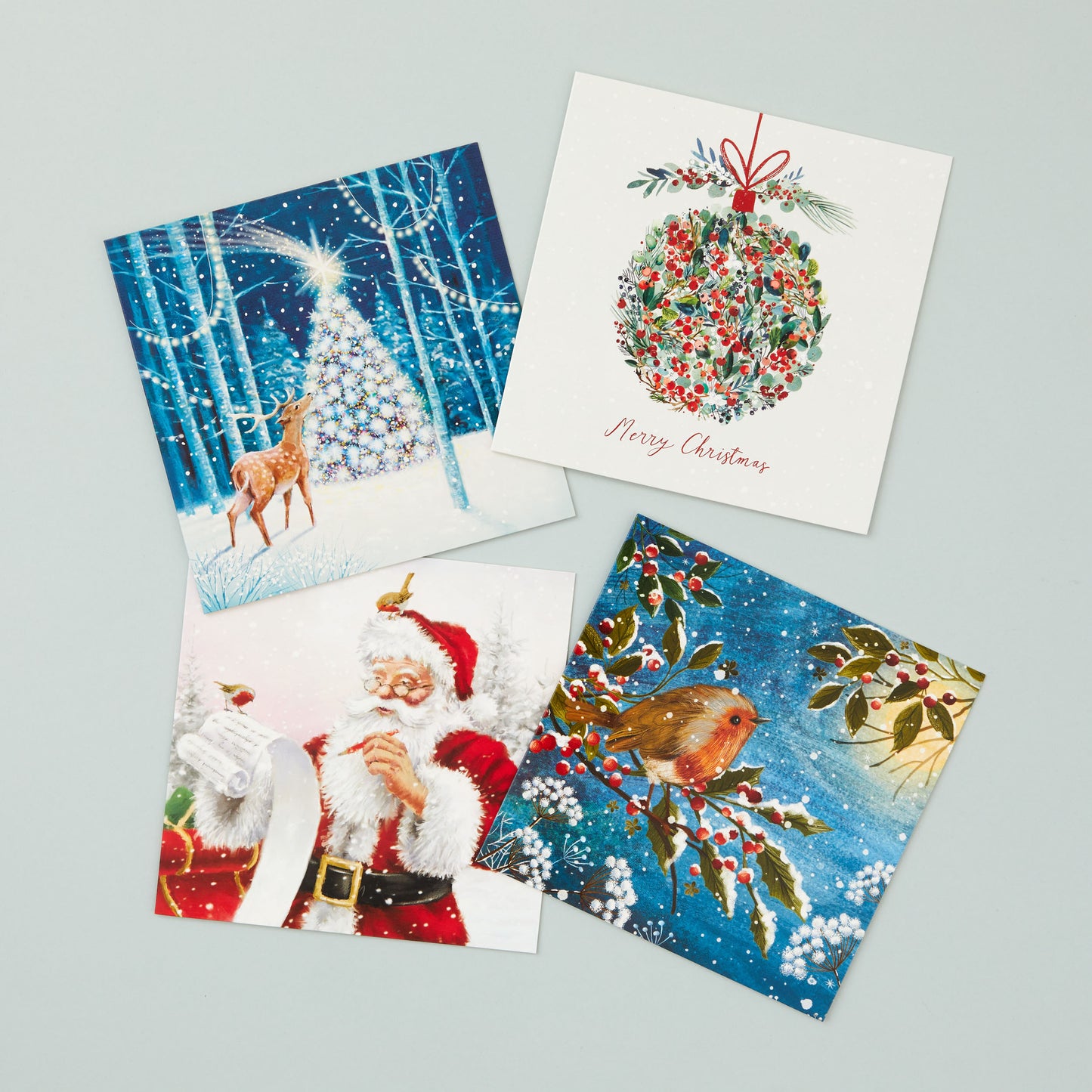 Four square Christmas cards in different designs - one with a reindeer and tree, one with a bauble design, one with a Santa design and one with a robin. 